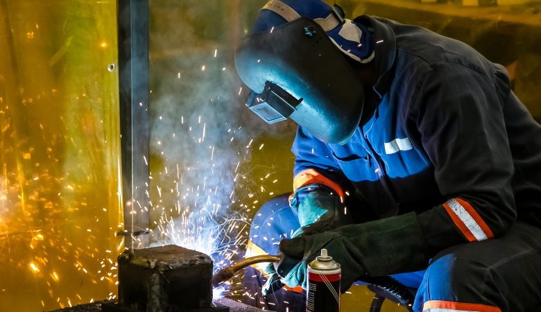 Welder profesional sedang mengelas baja dengan peralatan lengkap menghasilkan sambungan kuat dan rapi.